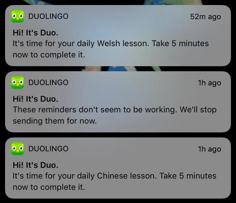Three Duolingo push notifications stacked on a phone lock screen, all sent as Duo. The first reads 'It's time for your daily Welsh lesson. Take 5 minutes now to complete it.' The second reads 'These reminders don't seem to be working. We'll stop sending them for now.' The third reads 'It's time for your daily Chinese lesson. Take 5 minutes now to complete it.'